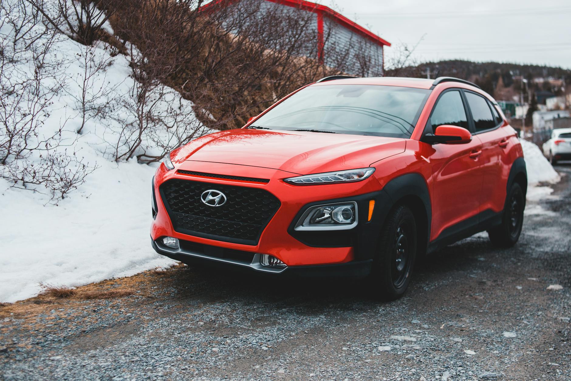 Czerwony SUV Suzuki Jimny zaparkowany na śniegu przed dojazdem do pracy