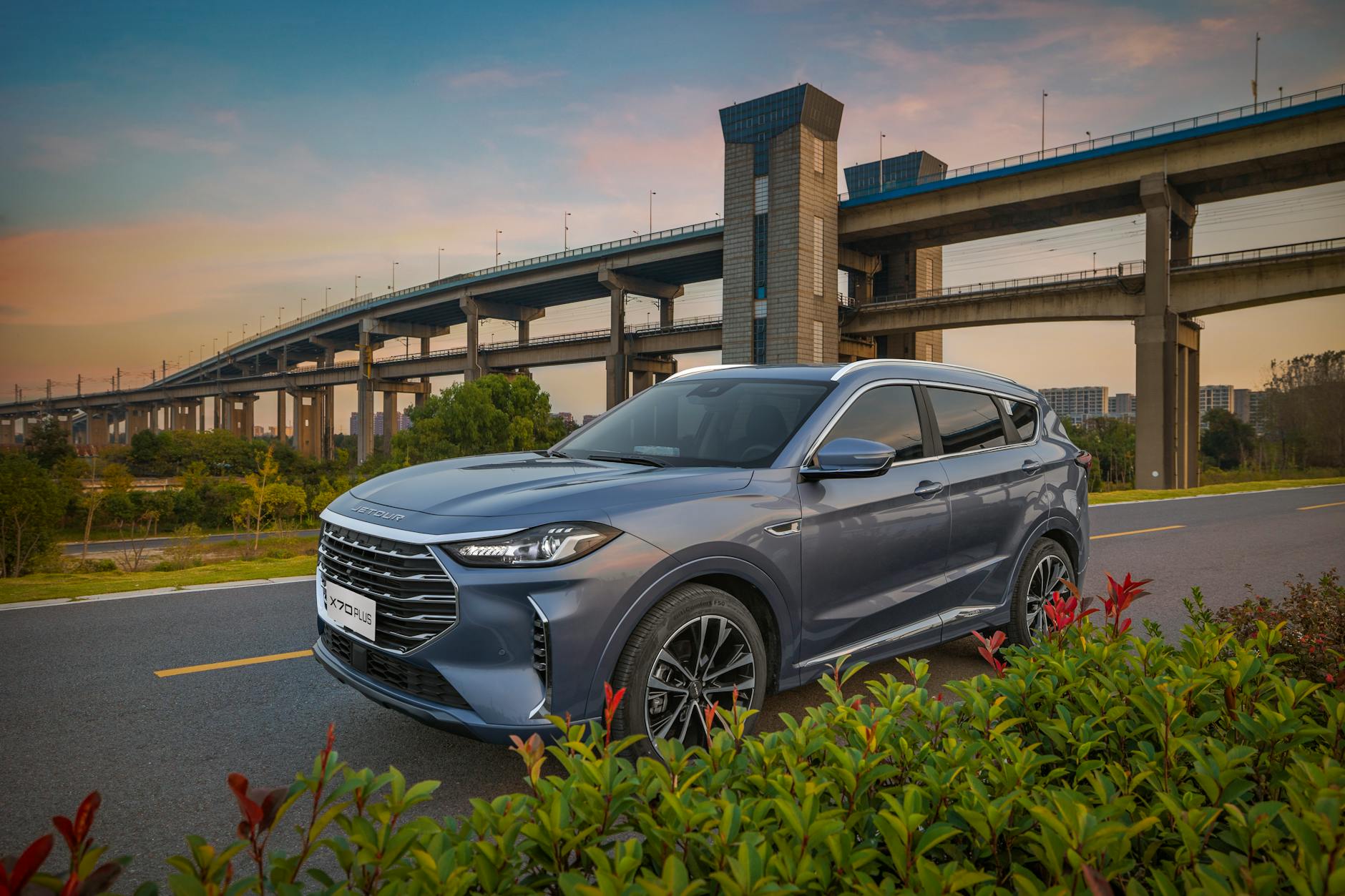 Niebieskie Suzuki Jimny zaparkowane na drodze przy moście o zachodzie słońca