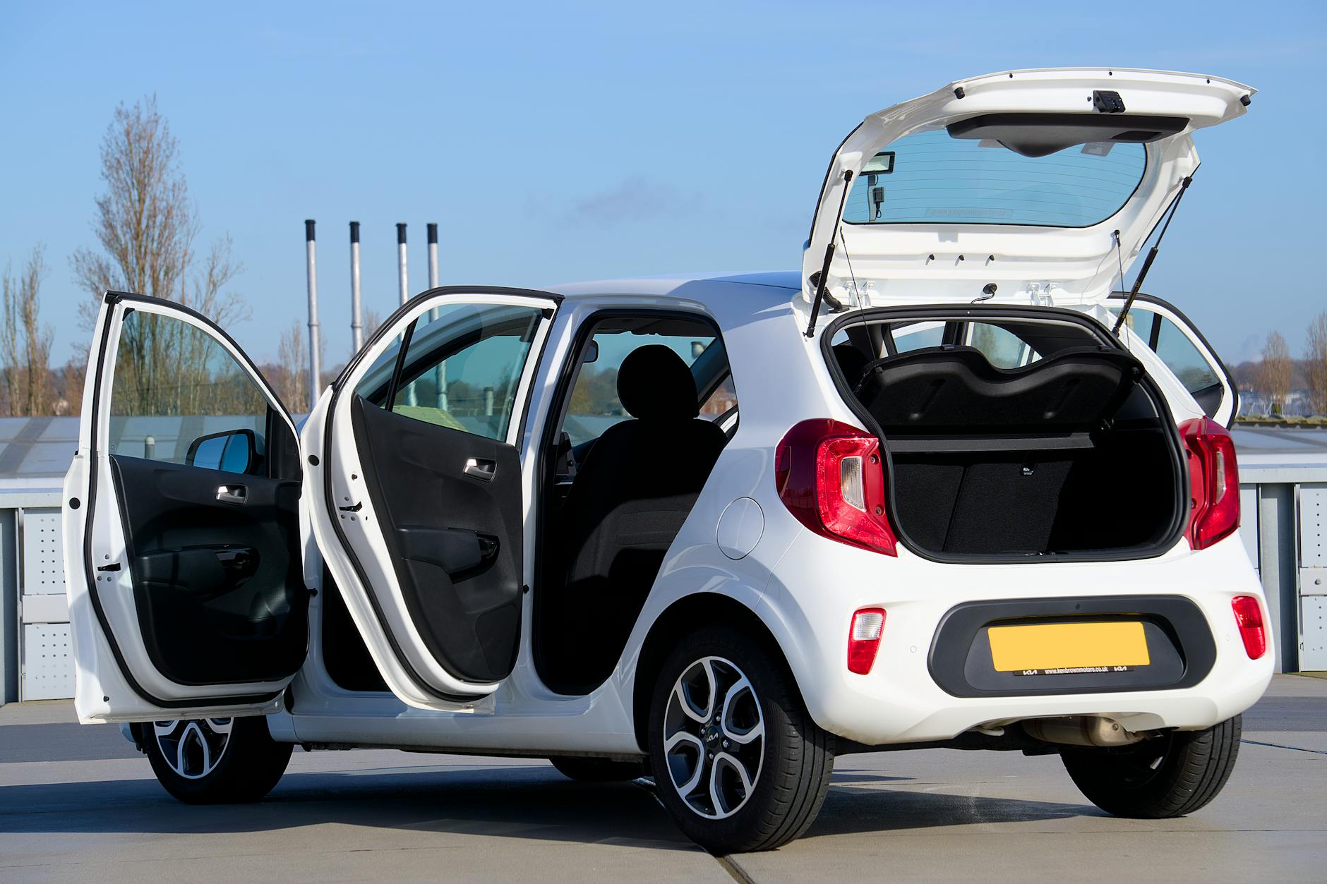 Białe Renault Clio z otwartymi drzwiami i bagażnikiem na ulicy