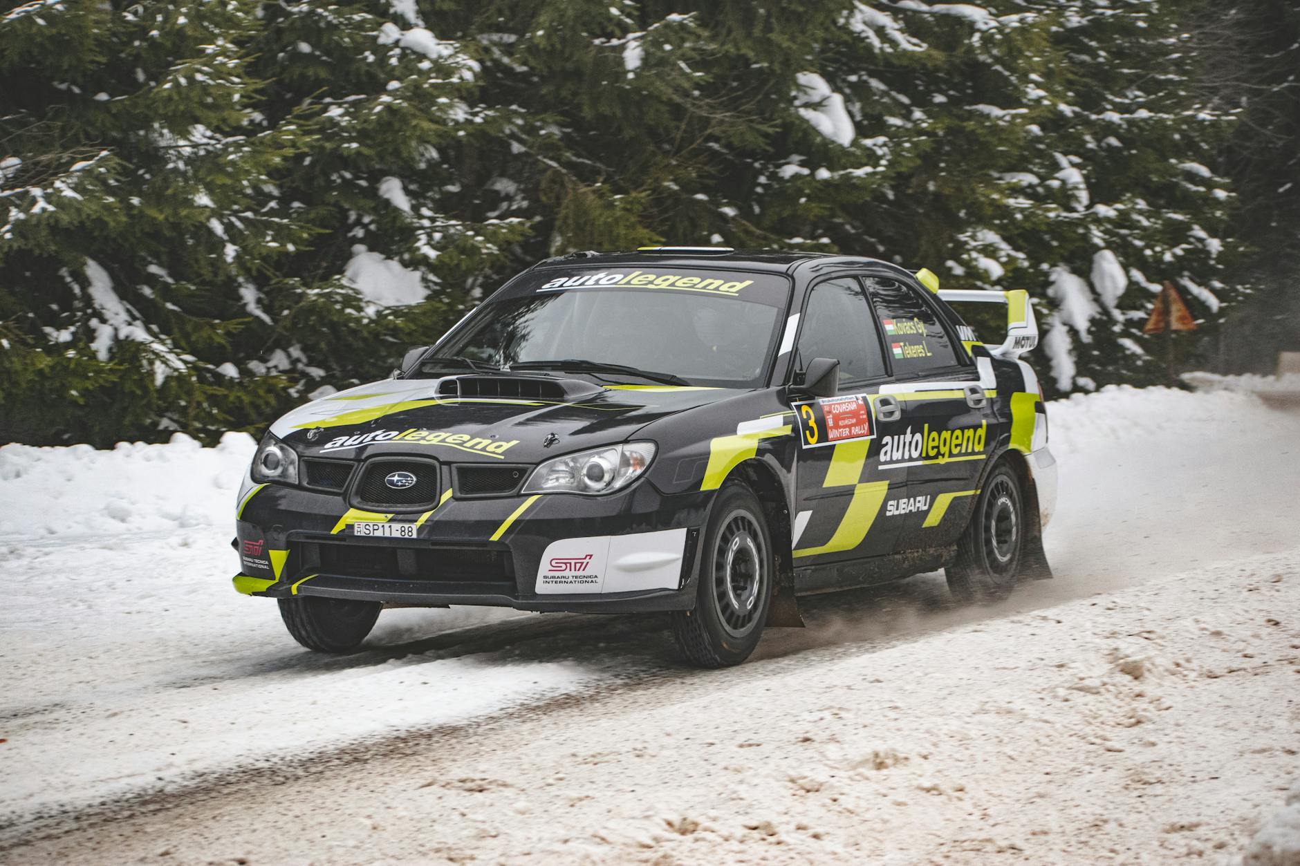 Samochód rajdowy pędzi po ośnieżonej drodze podczas zimowego wyścigu