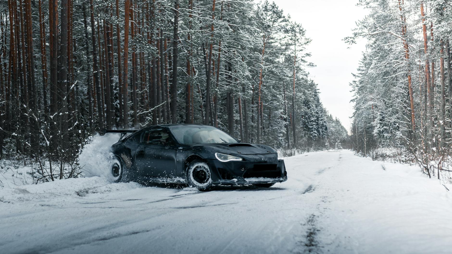 Sportowy Ford Mustang drifujący po ośnieżonej leśnej drodze