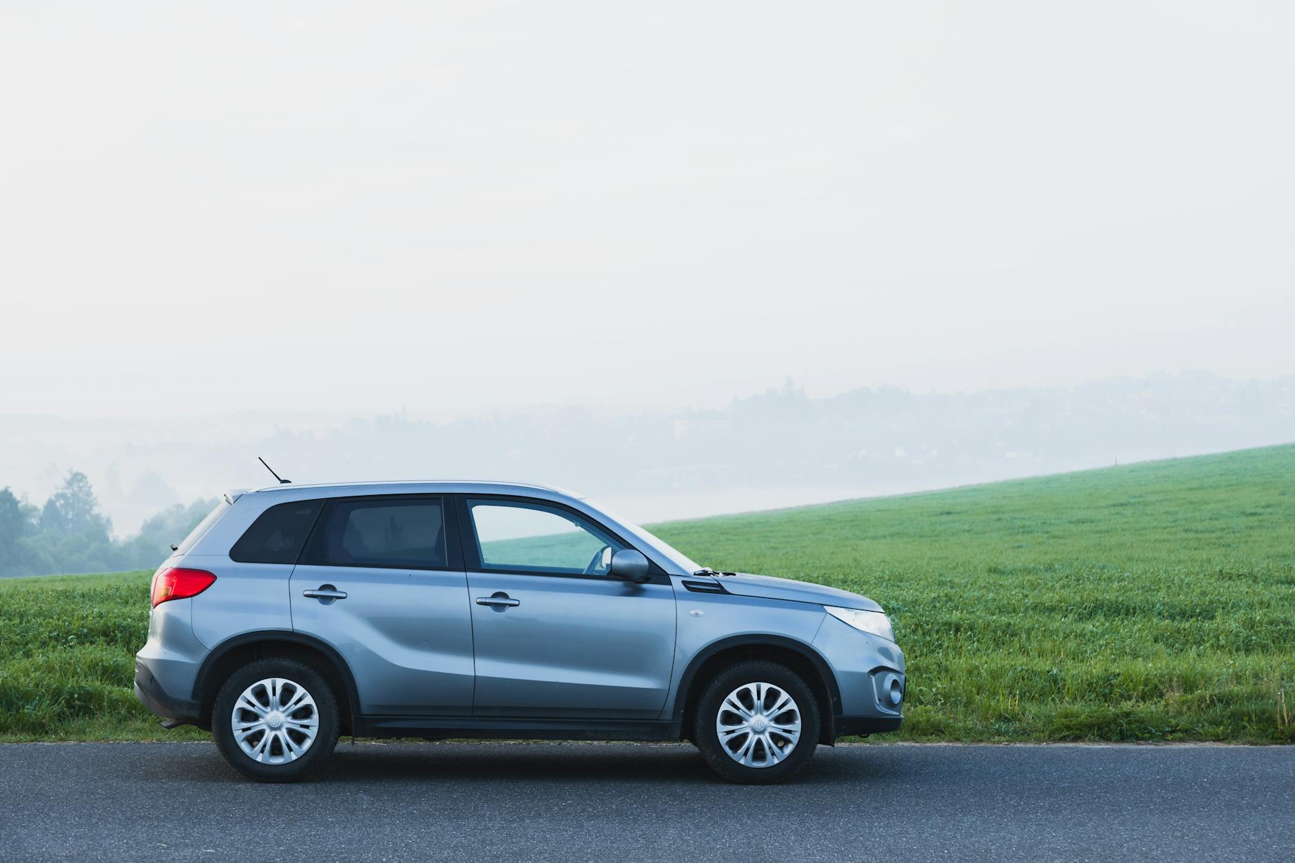 Srebrny SUV Mitsubishi na wiejskiej drodze we mgle