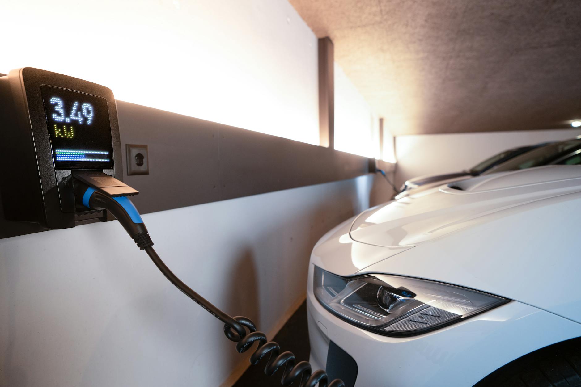 Biały elektryczny Citroën C-Zero ładowany na krytej stacji