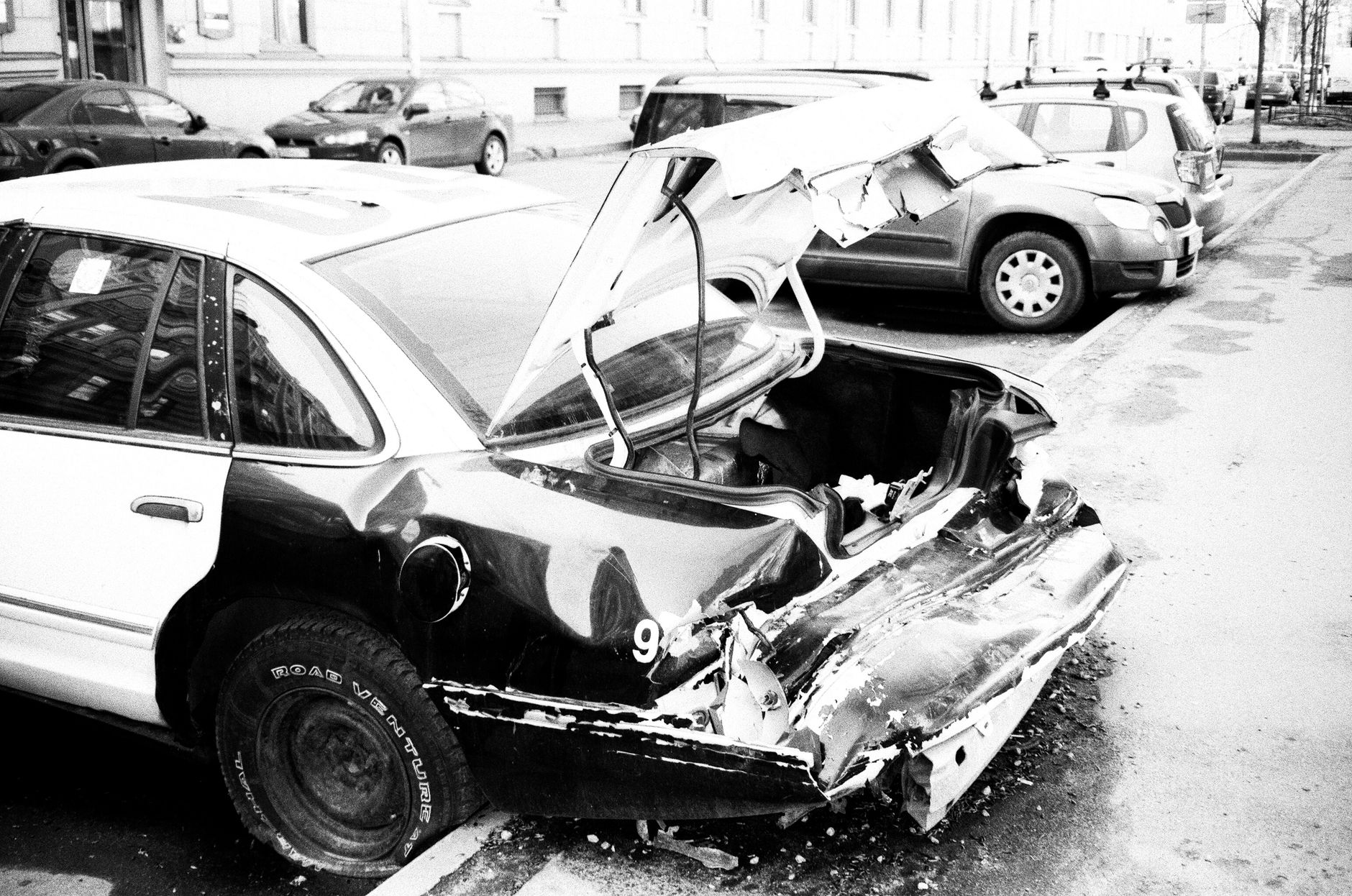 Czarno-białe zdjęcie rozbitego Lamborghini stojącego na ulicy miasta