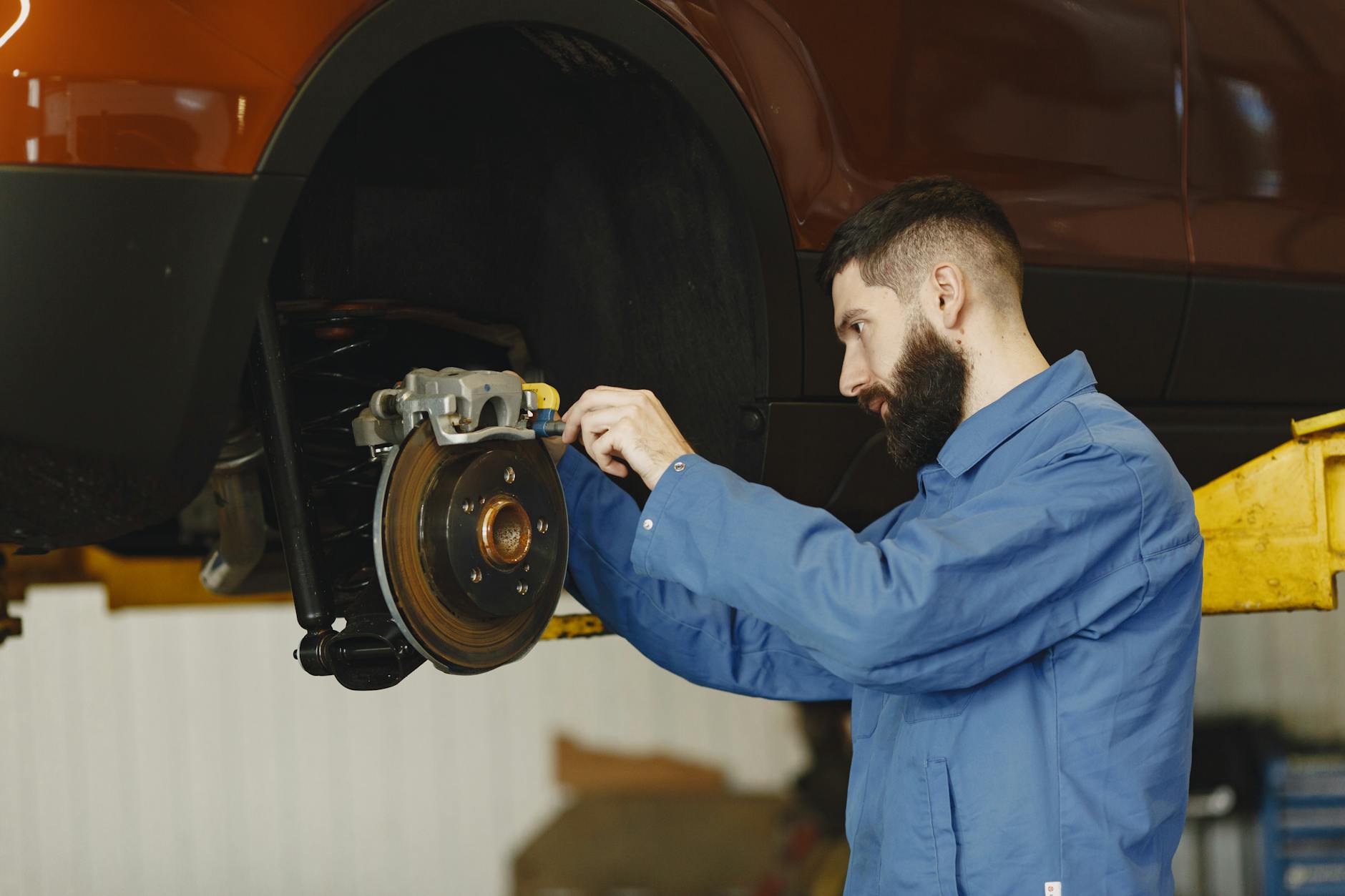 Mechanik w niebieskim kombinezonie naprawia hamulce w Volvo w warsztacie