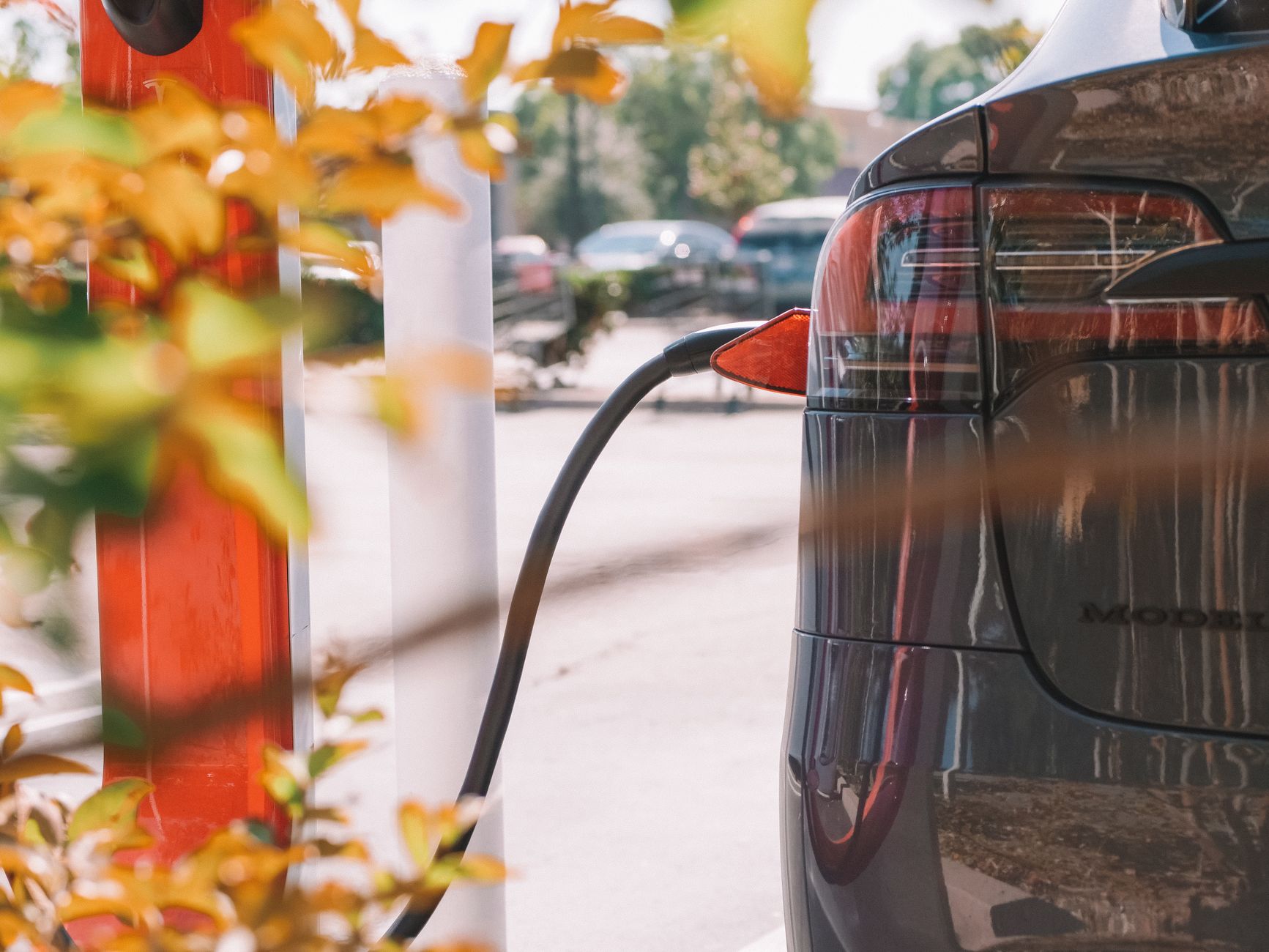 Ładowanie elektrycznego Fiata 500e przy stacji na tle innych aut