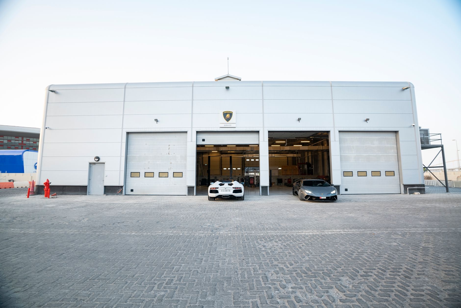 Luksusowy warsztat samochodowy z czerwonym Ferrari przed wejściem