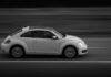 Czarno-białe ujęcie Volkswagena Garbusa jadącego drogą z boku